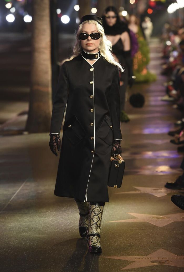 Εδώ βλέπουμε ένα μαύρο παλτό με χρυσά κουμπιά και μπότες με animal print