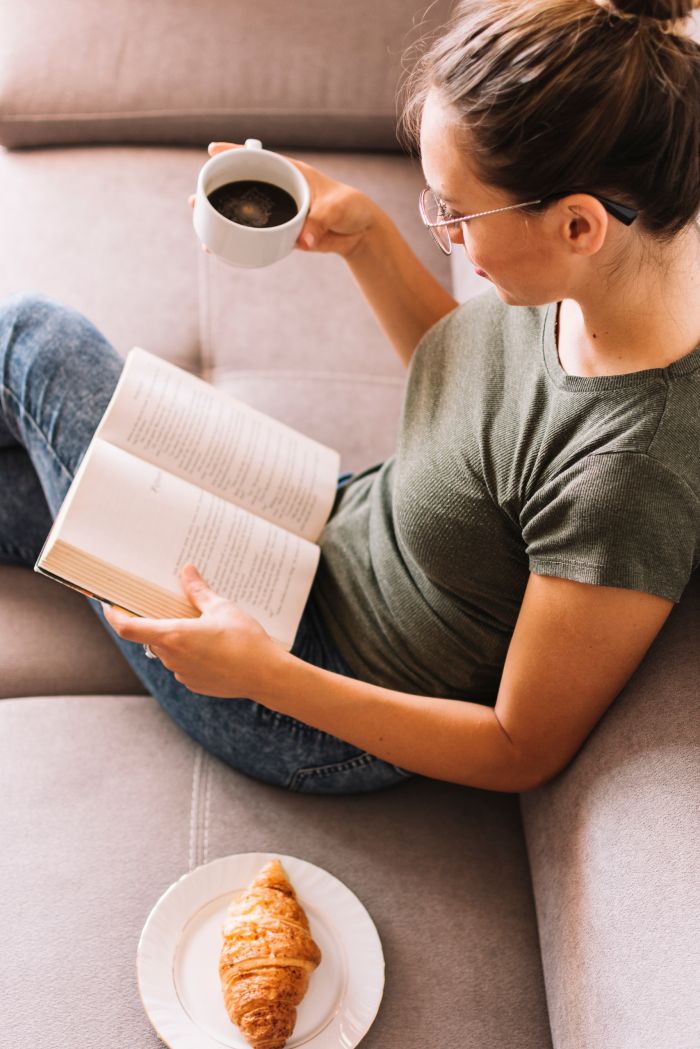 overhead-view-young-woman-sitting-sofa-reading-book.jpg