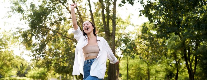 Happy people. Carefree asian girl dancing and enjoying the walk in park, feeling happiness and joy, triumphing