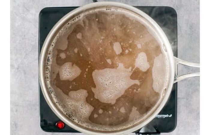 Βράζεις τον ζωμό κοτόπουλου μαζί με την κανέλα, το μπαχάρι και το μαύρο πιπέρι και, στη συνέχεια, χαμηλώνεις τη φωτιά και το αφήνεις να σιγοβράσει.