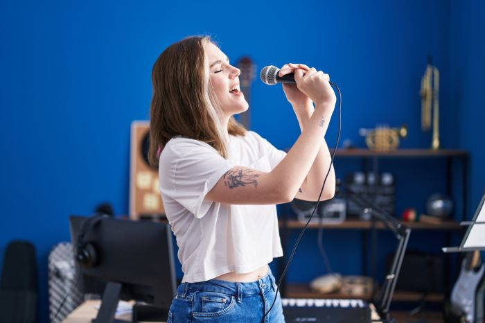 Young woman artist singing song at music studio