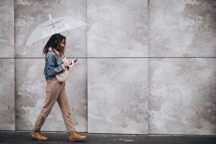 Young woman walking in the rain with umbrella