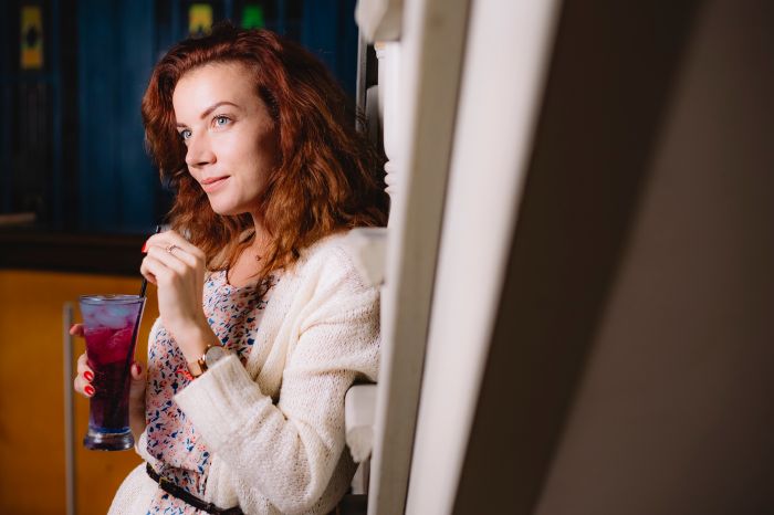 woman standing and holding cocktail glass with black plastic straw pipe