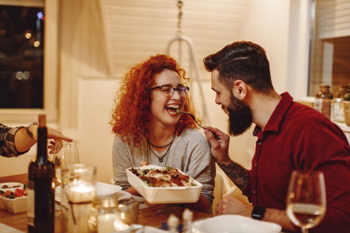 Young man feeding his girlfriend while having dinner at dining t