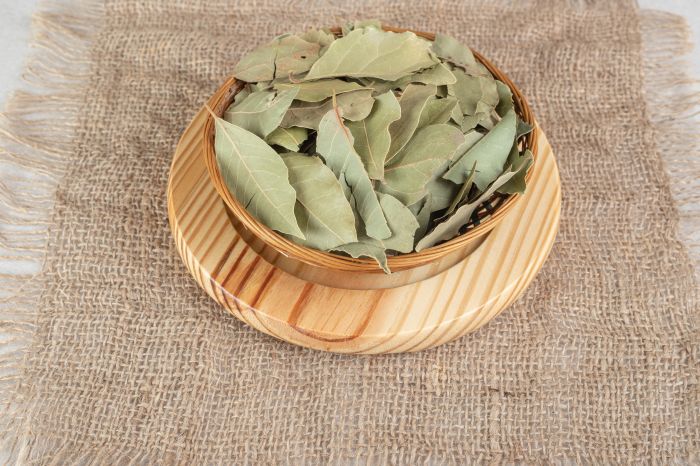 Dried green bay leaves on a wooden plate