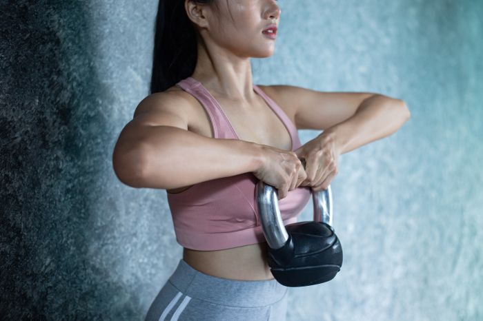 Asian girls are exercising with the Kettlebell in the gym.