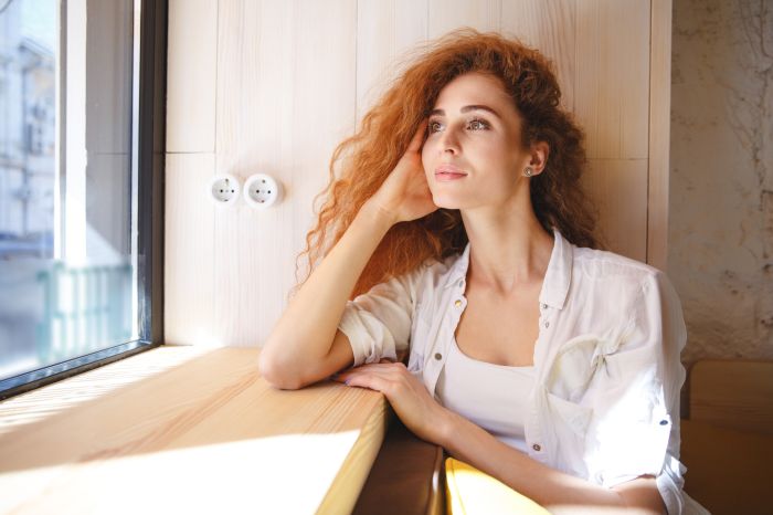 Smiling redhead young lady sitting in cafe