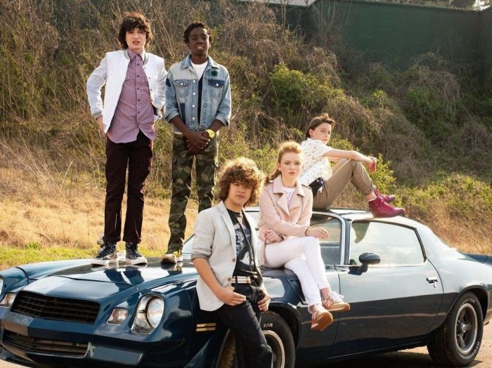 Οι πρωταγωνιστές ποζάρουν πάνω σε ένα αυτοκίνητο.