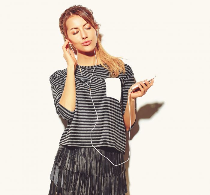 beautiful happy cute smiling blond woman girl in casual hipster summer clothes with no makeup isolated on white listening music in smartphone with headphones