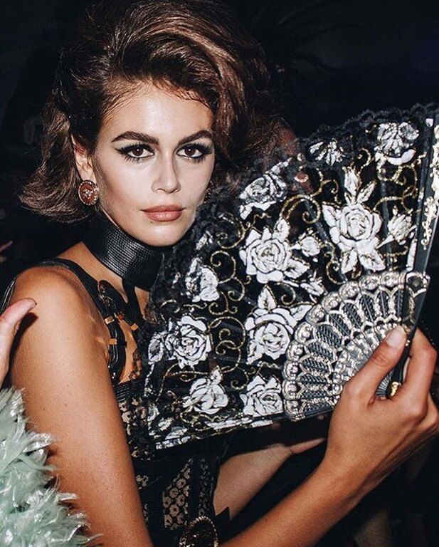 Η Kaia ολοκλήρωσε το look της με τσόκερ, ζώνη, τσάντα-φάκελο και ψηλοτάκουνες μπότες, όλα σε μαύρο χρώμα. 