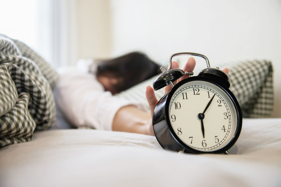 sleepy-woman-reaching-holding-alarm-clock.jpg