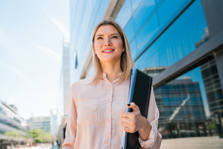 Business woman standing outside office buildings.