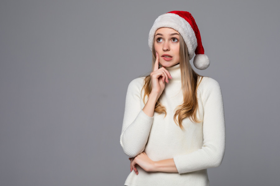 Young beautiful woman wearing a Santa hat over gray background thinking and looking to the side