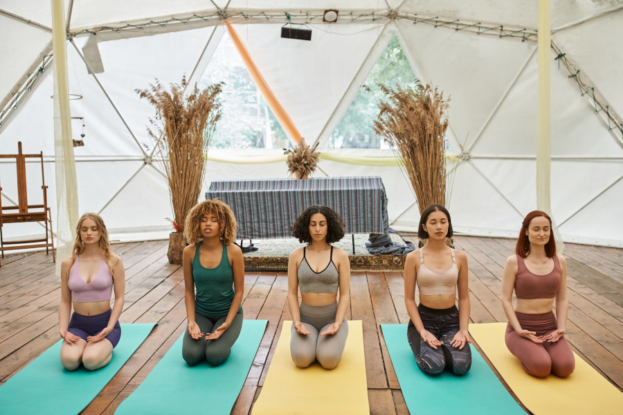 multiethnic women with closed eyes, in sportswear, meditating in thunderbolt pose