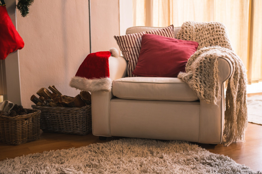 Woolen blanket, pillow and santa hat on sofa chair