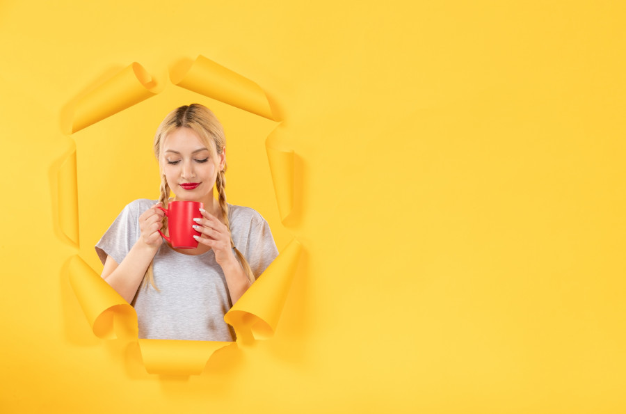 young woman drinking tea on torn yellow paper background facial advertising shopping