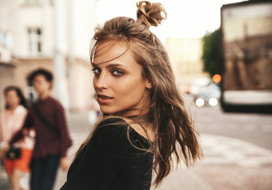 Portrait of beautiful cute blond teenager model without makeup in summer hipster clothes posing on the street background