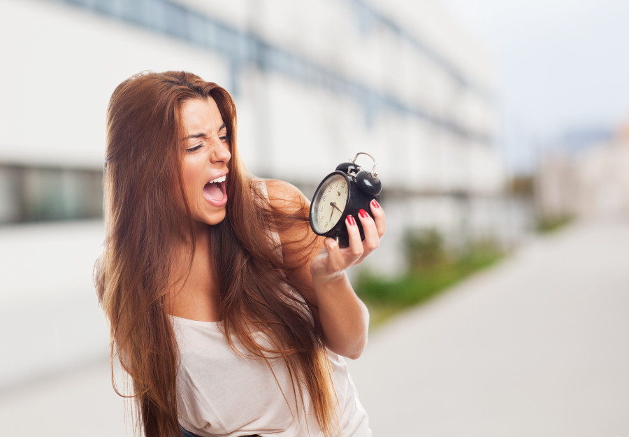 portrait of a young student screaming to alarm clock