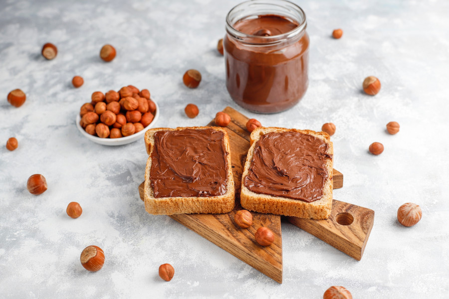 Chocolate spread or nougat cream with hazelnuts in glass jar on