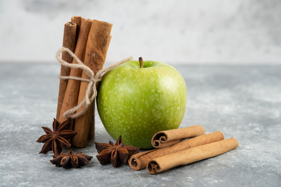Single green apple and cinnamon sticks on marble background