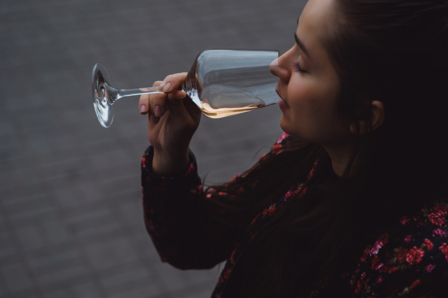 Stylish young girl drinks wine in a street cafe on a summer terr