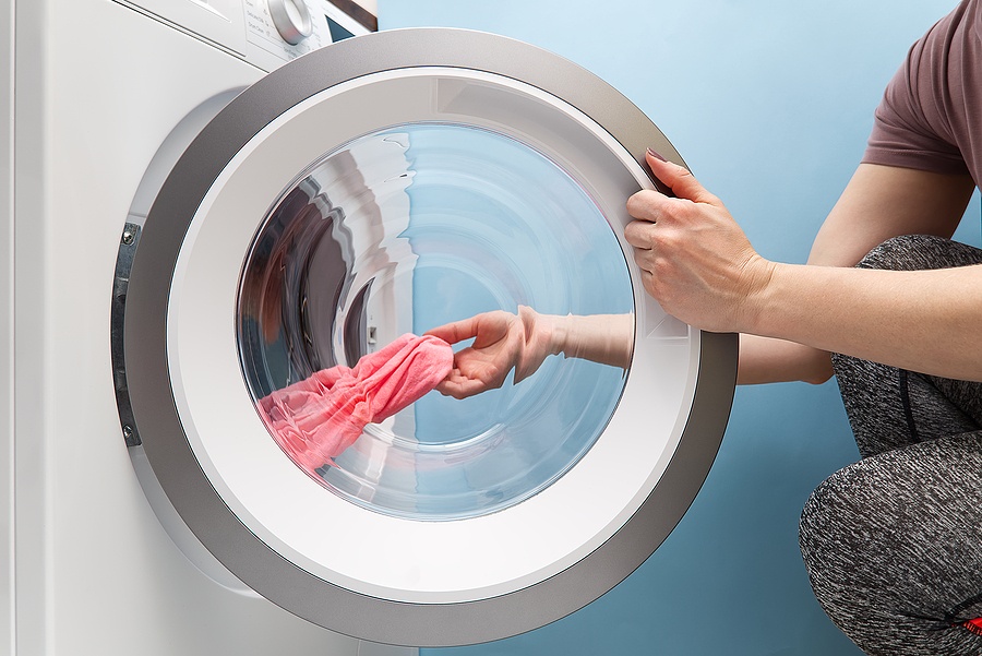 Girl Takes Out The Laundry From The Washing Machine. Woman Puts
